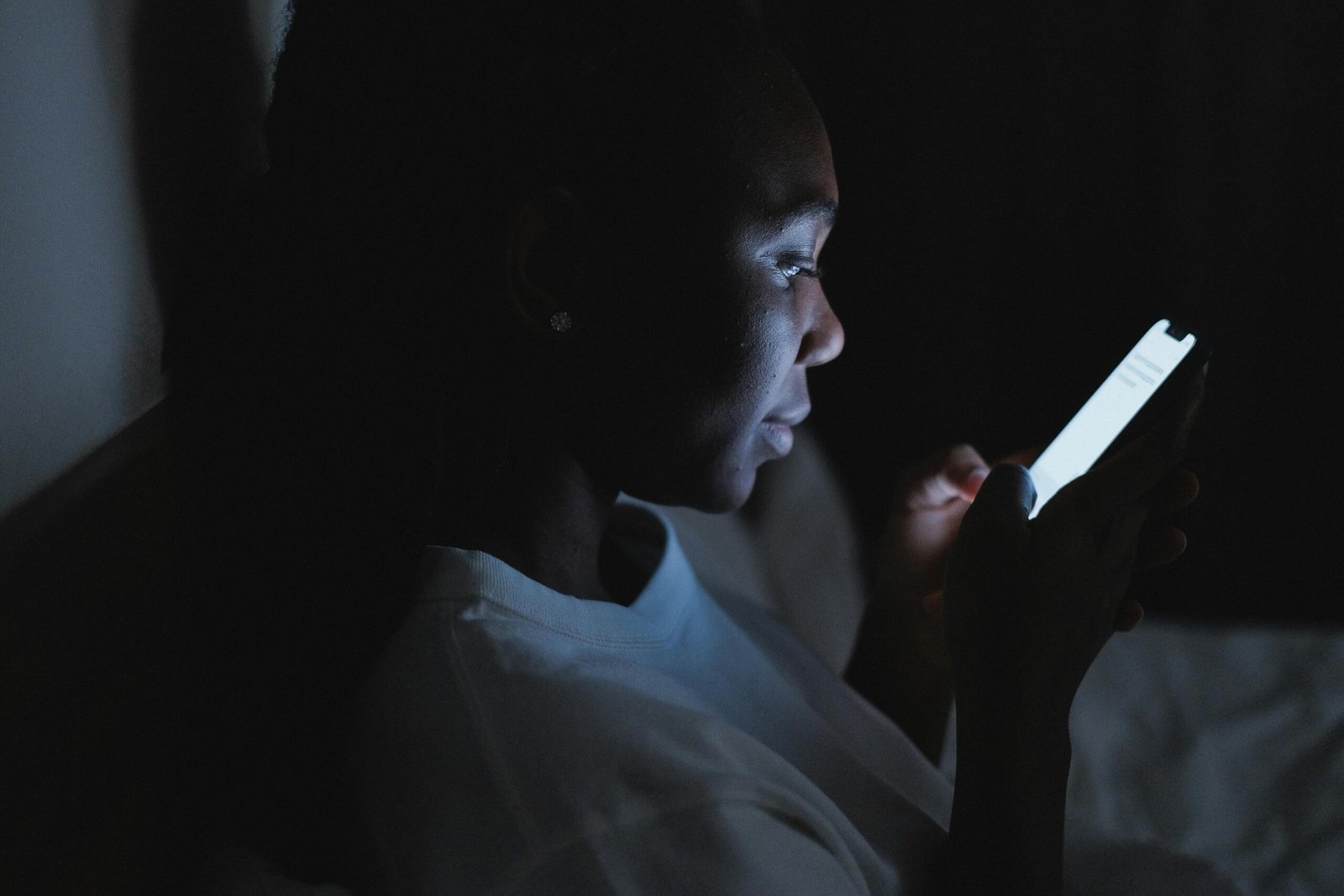 Woman in White Shirt Using Smartphone in Dark Room